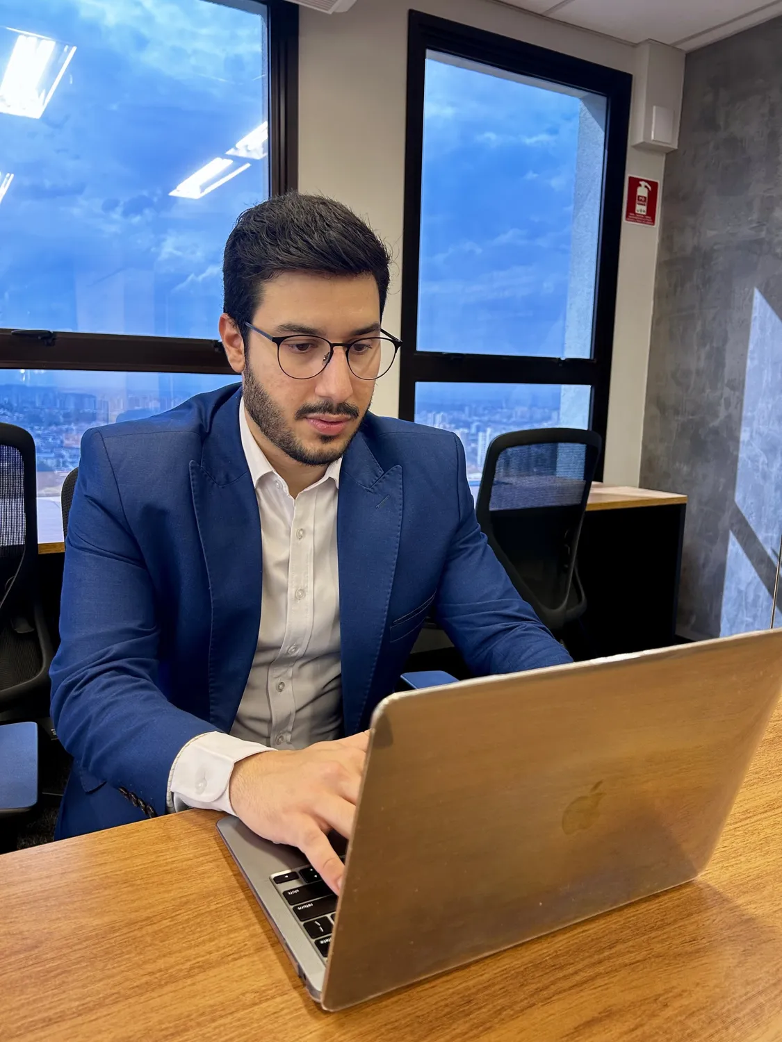 Bruno de Oliveira trabalhando no notebook em uma sala de reunião